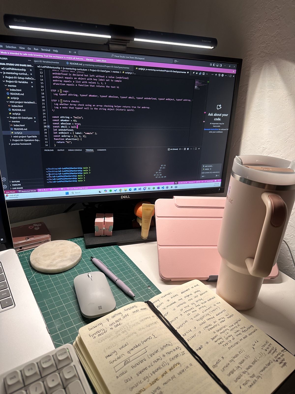 Simple desk setup with a laptop, notebook, and glass of water.